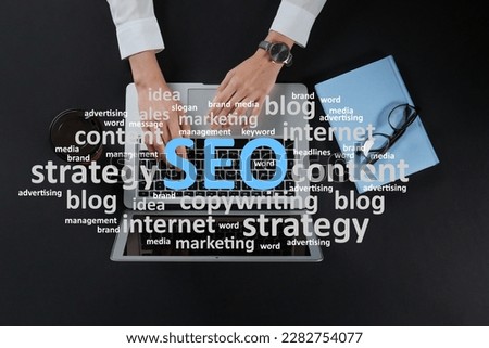 Search engine optimization (SEO). Cloud of words above copywriter with laptop at black table, top view