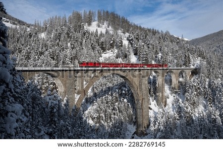 A picture of the train moving through the snowy mountains and forest