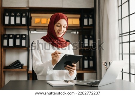 Young Arabic female entrepreneur wearing a hijab working online with a laptop at home office