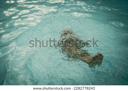 Photo From Above, abstract life background. Unrecognizable child body legs heel feet under pool water, deep swim dive away. Concept of weightless, uncertain future. Childhood problem. Sport exercises