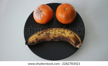 The rotten fruits (banana and oranges) making a sad face