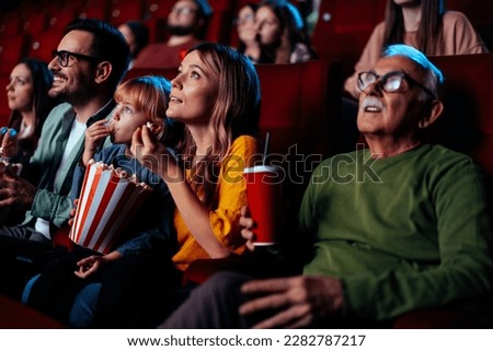 A group of diverse people are in a movie theater enjoying a movie, having popcorn and drinks. Royalty-Free Stock Photo #2282787217