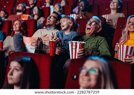 A grandfather and his granddaughter are in the movies enjoying themselves and having fun laughing out loud. Royalty-Free Stock Photo #2282787259