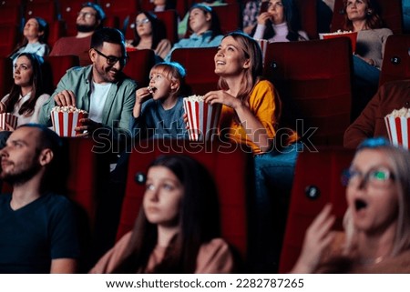 A young Caucasian couple is with their child in the cinema, watching a movie. Royalty-Free Stock Photo #2282787265