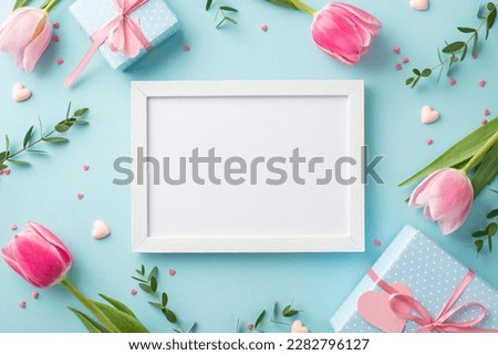 Mother's Day concept. Top view photo of photo frame spring flowers tulips present boxes small hearts and sprinkles on isolated pastel blue background with empty space