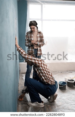 Young couple measure wall with measuring tape doing apartment repair together. Renovation, family, love concept. Copy space