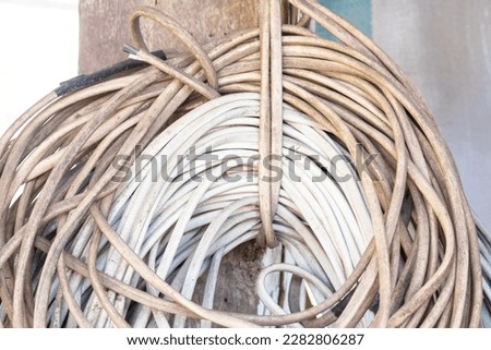 Coiled pile of old electrical, electric wire white brown wires hanging on wooden pole. Concept of recycling and disposal of electronic waste. Precious metals in old.