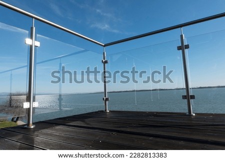 View of the lake from the hotel's terrace with a glass railing Royalty-Free Stock Photo #2282813383
