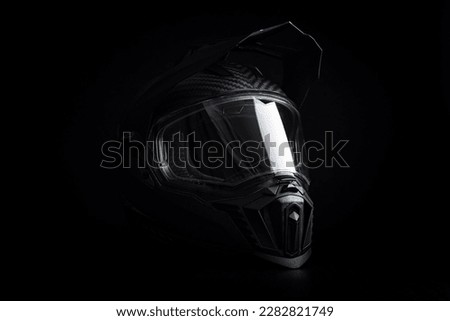 Black carbon motorcycle helmet. Offroad motocross helmet with shieldon the black background. Royalty-Free Stock Photo #2282821749