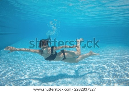 young woman dives into the swimming pool with bubbles. Underwater photo