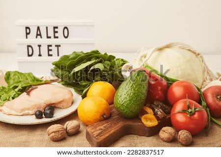Aesthetics Paleo diet concept with text. Fruits,vegetables, chicken meat, dry fruits, greens on wooden cutting board. Royalty-Free Stock Photo #2282837517