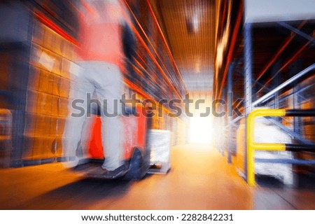 Blurred Warehouse Space. Workers Unloading Package Boxes. Tall Shelf Storage Supplies Warehouse. Supply Chain Shipment Goods. Distribution Shipping Warehouse Logistics	
