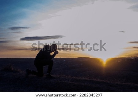 Prayer. Man on his knees praying. Against the background of the sky and sunset. Forgiveness of sins and repentance. Easter Royalty-Free Stock Photo #2282845297