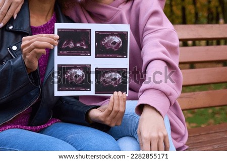 Woman with sonographic images sitting beside her partner in public park