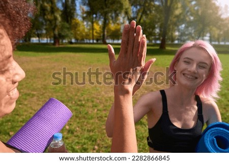 Smiling pleased female athletes greeting each other before outdoor workout