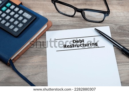 Financial management concept. Debt Restructuring message written on the white paper on office table with a pen, calculator and eyeglasses at the side