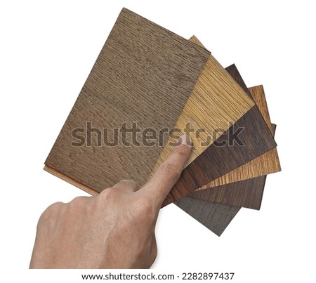 male architect's hand selecting stacked of wooden laminated flooring tiles sample for interior renovation, top view, isolated on background with clipping path. engineering floor tiles samples. Royalty-Free Stock Photo #2282897437