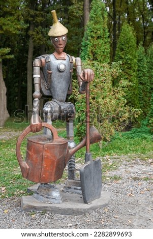 The figure of a gardener made of scrap metal. Man figure made from rusty metal machine parts. Iron Man in the Garden.