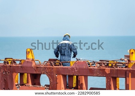 Seaman working on deck of the container vessel. He is preparing ship to enter shipyard. Royalty-Free Stock Photo #2282900585