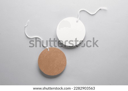 Empty round craft and white price tags with string on gray background. Template for design