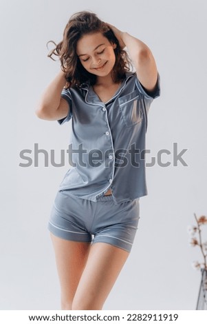 Young woman in blue pajamas suit of shorts and shirt on white background Royalty-Free Stock Photo #2282911919
