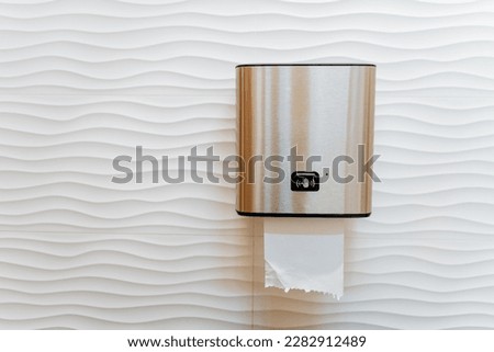 Automatic paper towel dispenser, piece of paper sticking out of the dispenser in the toilet, paper dispenser, clean hands, cleaning machine. High quality photo Royalty-Free Stock Photo #2282912489