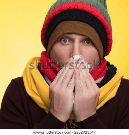 Young sad man wearing burgundy sweater yellow scarf hat hold napkin tissue blowing nose sneeze isolated on plain yellow background studio portrait Healthy lifestyle ill sick disease treatment cold sea Royalty-Free Stock Photo #2282923547