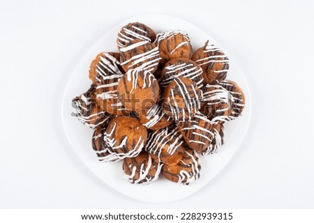 Small cupcakes with cocoa and white and milk chocolate with cream on a white background close-up.