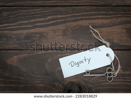 The key of dignity concept.  Silver key  with a label on wood table.