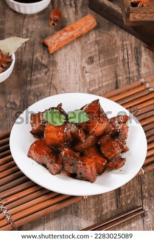 Pork in black bowl at dark slate background. Pork Adobo or Adobong Baboy is sichuhan cuisine dish with braised pork belly, bay leaves, soy sauce, vinegar and spices. Chinese food Royalty-Free Stock Photo #2283025089