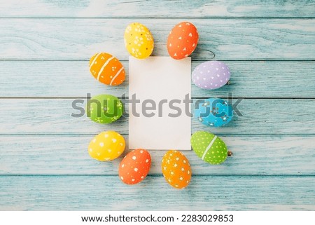 Easter Day Concept. Flat lay holiday banner background web design white colorful easter eggs composition with paper rectangle blank on blue wood background with empty copy space, celebration greeting