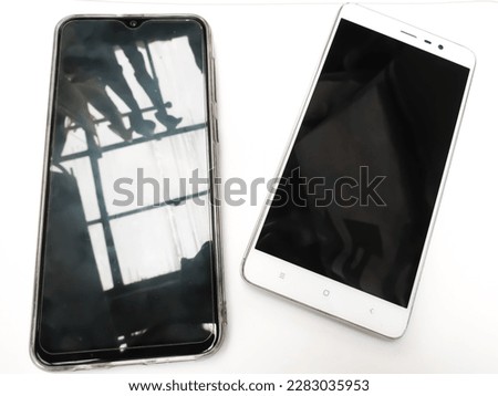 Two cellphones, one in shiny new condition and the other in used condition with a dirty, greasy black screen. Shot Close Up From Above On The Table. White background. JPG or JPEG Image. PNG Wallpaper