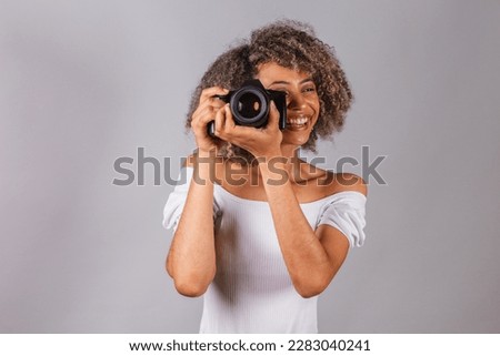 beautiful Brazilian woman, black,
holding photo camera, photography as a hobby, tourist.