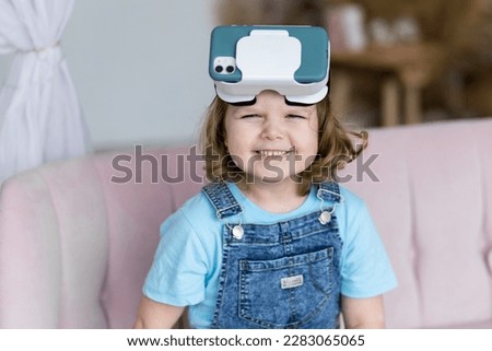 Cute little girl with vr glasses. Kid's experience with virtual reality. Looking surprised, excited, happy, smiling. Using modern gadget for playing games, watching movies, cartoons at home