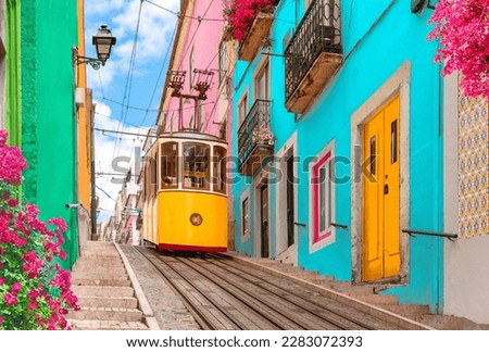 Lisbon, Portugal - Yellow tram on a street with colorful houses and flowers on the balconies - Bica Elevator going down the hill of Chiado Royalty-Free Stock Photo #2283072393