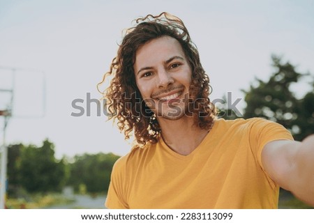 Close up young cheerful happy man 20s wear yellow t-shirt doing selfie shot pov on mobile cell phone walking rest relax in spring green city park outdoors on nature. Urban lifestyle leisure concept