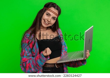Excited happy young hippie woman typing on laptop computer, working on project, enjoying results, winning lottery, celebrating success online shopping win. Girl isolated on green chroma key background