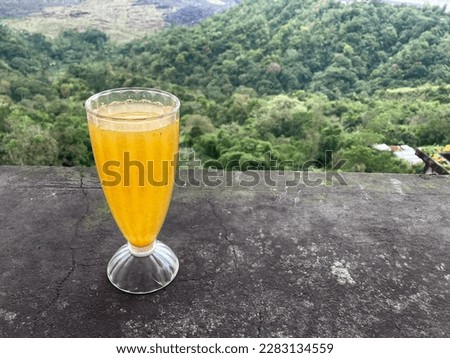 Hot and fresh orange water served in the glass with beautiful green mountain view