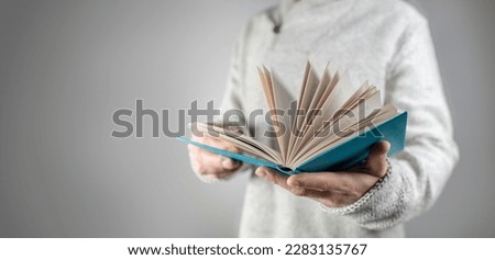 Man in white cardigan holding and reading open book background concept for education, studying and knowledge