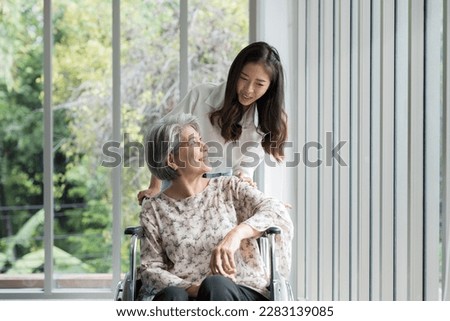 Young Asian woman nurse taking care senior elderly woman patient with careful on wheelchair. Happy smiling female caring senior old woman on wheelchair with kindly in nursing home Royalty-Free Stock Photo #2283139085