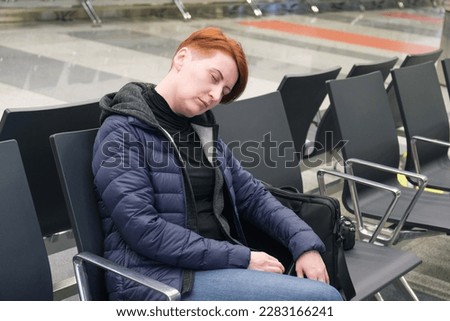 Woman sleeps in the departure area of an international airport. The flight passenger overslept the departure time. Royalty-Free Stock Photo #2283166241