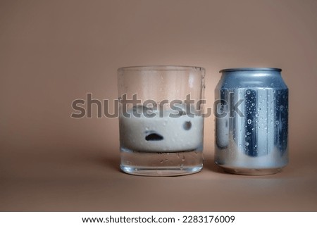 Glass of fresh cold chocolate drink sitting next to its can over blurry background