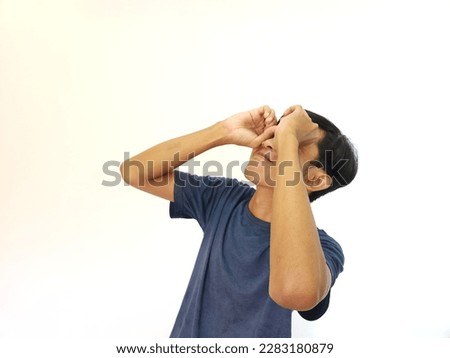 Funny obvious peeking Asian man in blue shirt isolated on white background