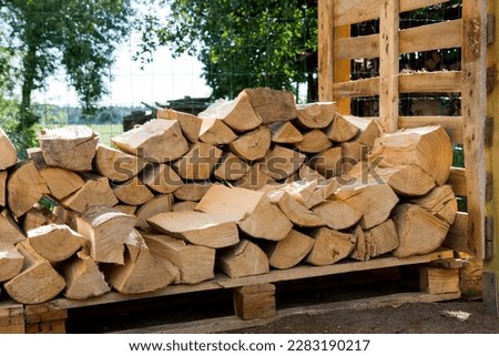 Pile of firewood in the summer stocked outdoors in a shed, being prepared for winter