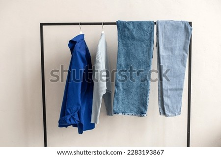 There are blue things hanging on the hanger. A set of blue clothes. Jeans and sweaters