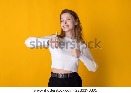 Young caucasian woman showing thumbs up against bright yellow background