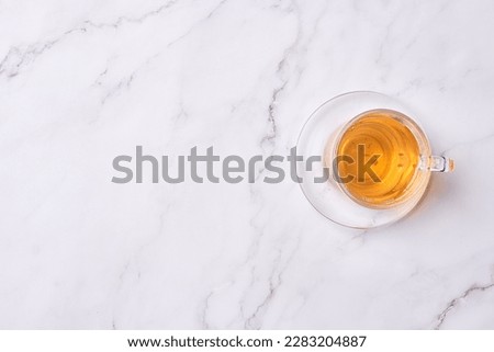 a cup of tea on a white marble surface with copy space in the top right corner, and an overhead image of a glass