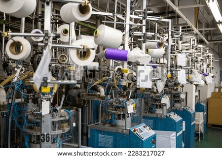 Textile industry with knitting machines in factory. Textile industry with a loom on the production of kapron tights. Royalty-Free Stock Photo #2283217027