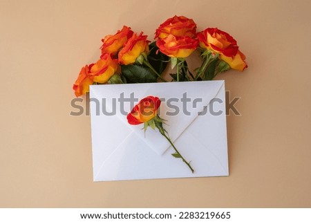 Beautiful red roses flowers in postal envelope on neutral beige background, copy space for text, spring time, greeting card for holiday. Flower delivery. Delicate red yellow roses. Minimal trendy