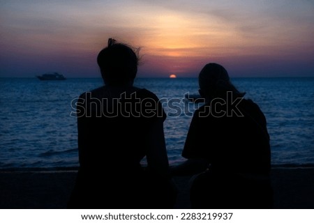 Safaga - Egypt mother and daughter on the beach watching the beautiful sunrise. Silhouette of a womans on the Red Sea